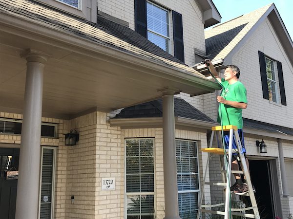 Man Over the Ladder and Cleaning the Roof