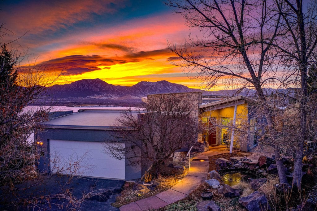 sunset photo of a home by a lake and mountains